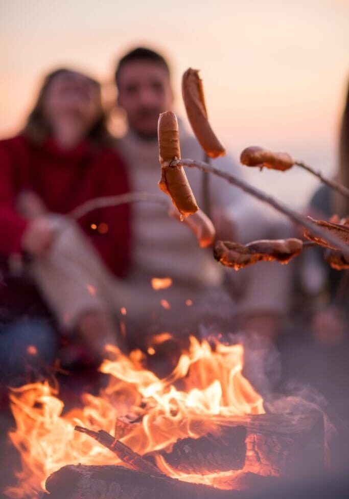 group-of-young-friends-sitting-by-the-fire-at-2FVTGEP